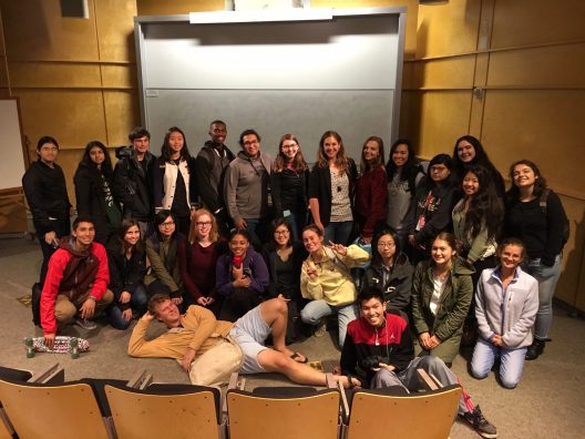 A group of students stand in an auditorium.