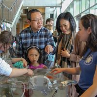 A family looks at a table exhibit during the UW Aquatic Science Open House