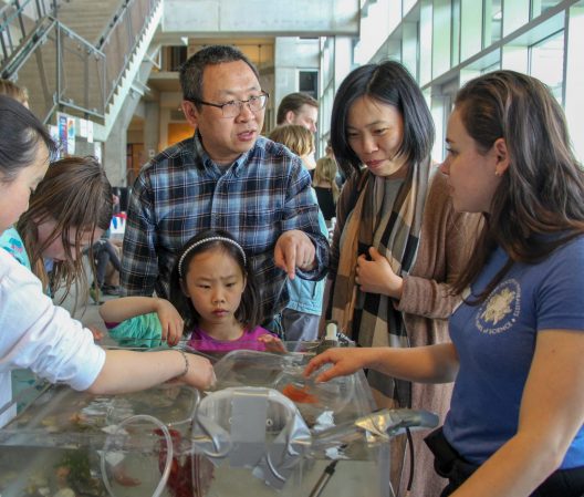 A family looks at a table exhibit during the UW Aquatic Science Open House