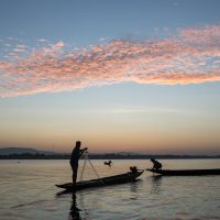 A man standing on a canoe on the Mekong river in Laos