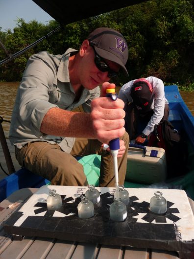 Benjamin Miller sampling water on a boat in Cambodia