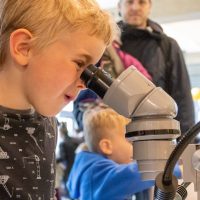 A young boy looks into a microscope.