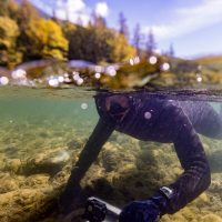 Nicholas Chambers pictured snorkeling underwater, with the top half of the photo above the water, and the bottom half under the water.
