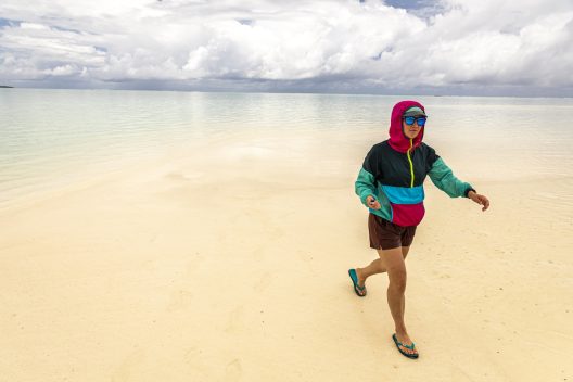 Amelia DuVall walks across a white sand beach