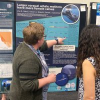 Zoe Rand at a conference pointing to a research poster