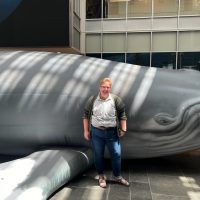 Zoe stands in front of a large sculpture of a whale
