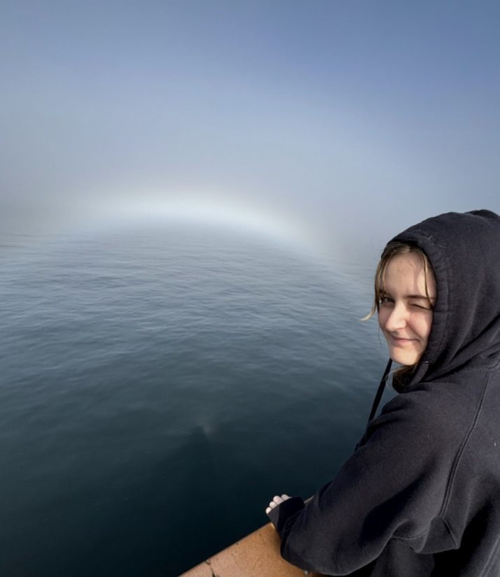 Anna Kleven stands on a pier overlooking the water on a foggy day.