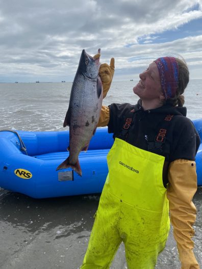 Naomi Prahl holds up a fish with the sea in the background