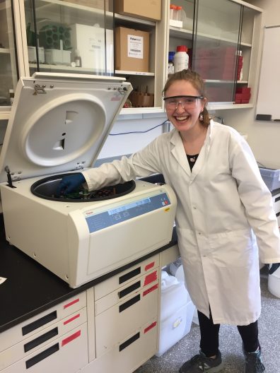Jenny Stern stands in a lab near a big machine.