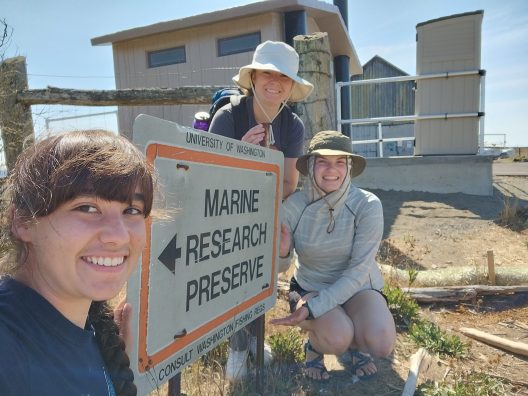 Three people pose in front of a sign saying 'Marine Research Preserve'.
