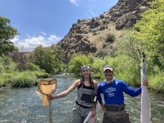 Two people stand with nets in a river