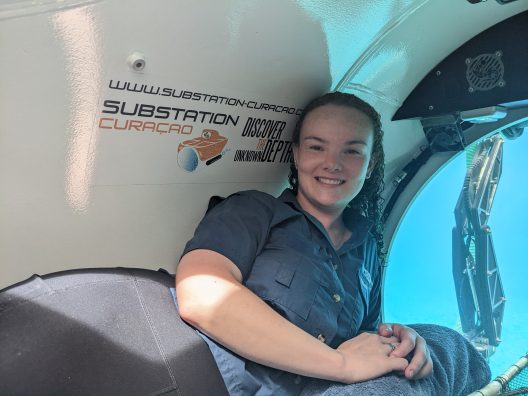 Sarah sits inside a submersible.