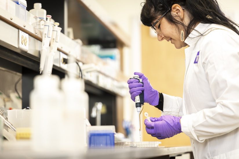 Mollie Ball in the lab holding a syringe while doing DNA research.