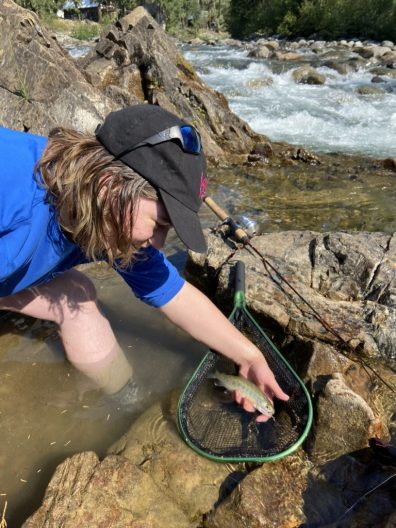 Andy Gardner leans down to a net folding a fish.