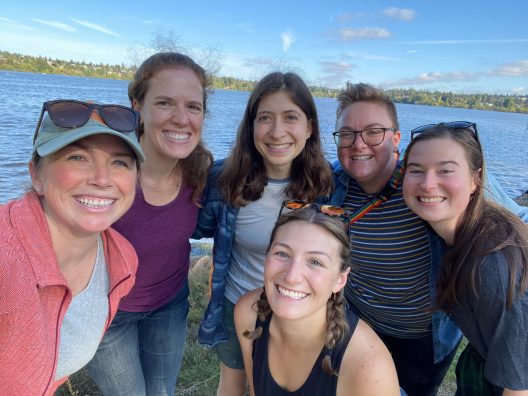 A group of SAFS students post for a photo with a lake in the background.